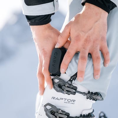 Skier clipping a Carv sensor onto their ski boot strap